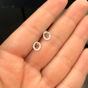 Paire de boucles d’oreilles circulaires argentées avec une moitié inférieure rose pâle. Pair of circular silver earrings featuring a glossy pale pink lower half.